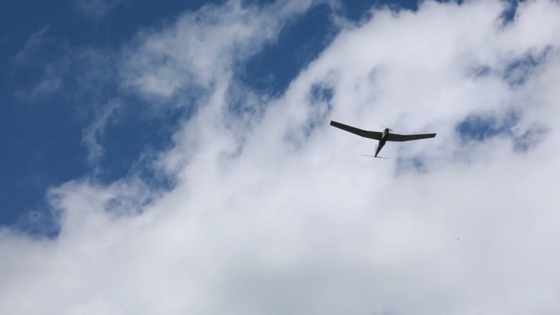 Uncrewed aircraft in flight above open terrain.