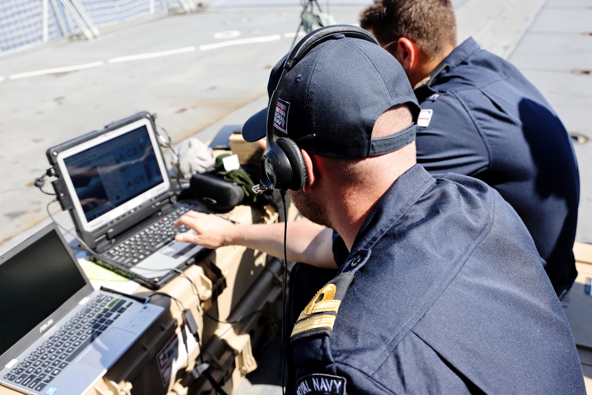 Royal Navy personnel working with remote-control equipment on a vessel deck.